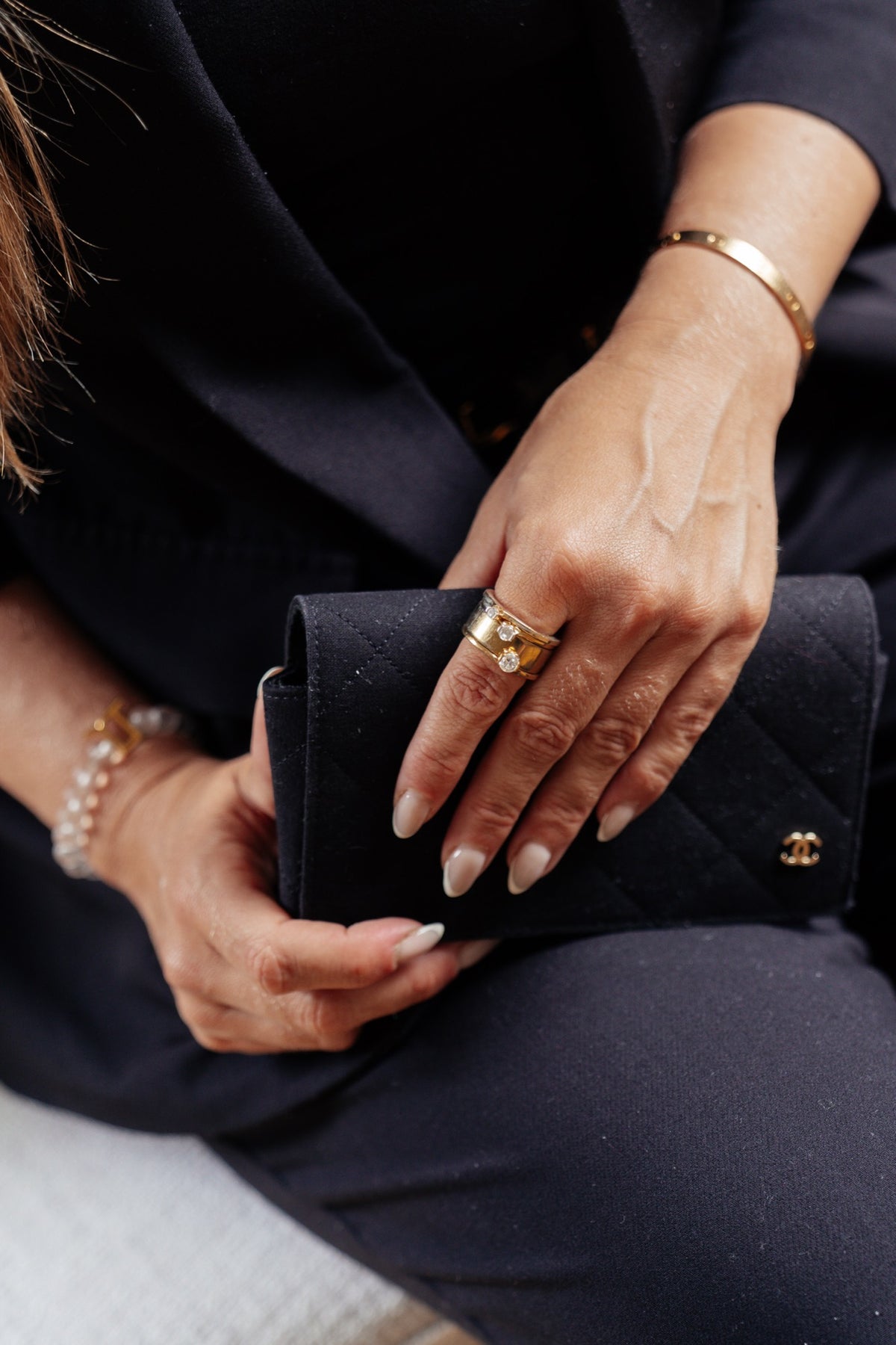 Hand mit MIONA Aufsteckringen in Gold an einer schwarzen Clutch