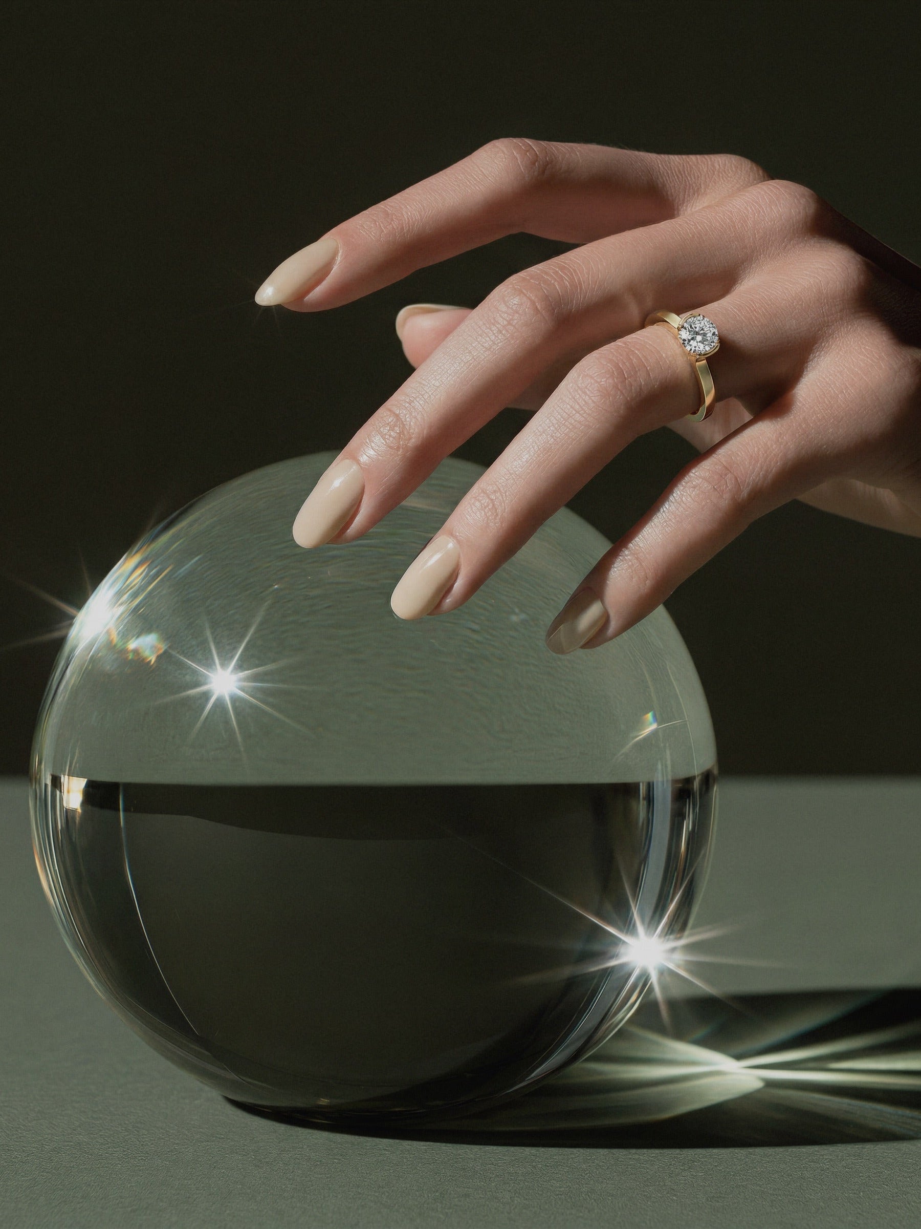 Hand mit MIONA Aufsteckring in Gold über einer Glaskugel